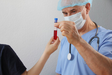 patient and the doctor, therapist, pediatrician, hold together a test tube with a blood test, the concept of medical treatment, diagnosis of the disease, insurance, professional care and trust