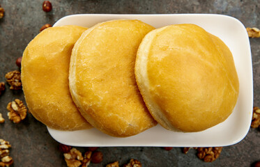 Three baked round patties on a white square plate.