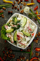 Fresh vegetable salad with mayonnaise in a square white plate. On a gray concrete textured background