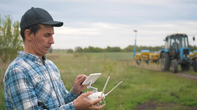 A male farmer operates an unmanned aerial vehicle to monitor the sowing of cereal seeds on agricultural land. Use of modern technologies in agriculture for high yield, good seedlings.