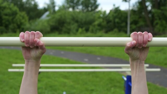 The young guy is trying to catch up on the horizontal bar, but he does not succeed. Newbie training in the fresh air