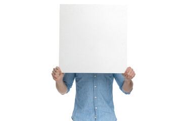 young casual guy covering face with empty board