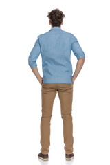 back view of young casual guy holding hands in pockets
