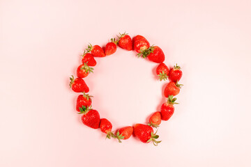 Frame made with organic and tasty strawberries in circle on pnk background. Summer composition, minimal style