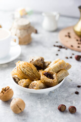 Baklava in a plate on the table. next to it is coffee, nuts and coffee beans