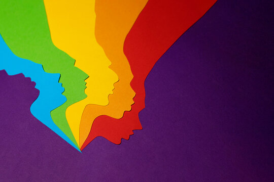 The human rainbow colored paper profiles cut out on a purple background. There is a place for text. The photo of paper art was made for your design.
