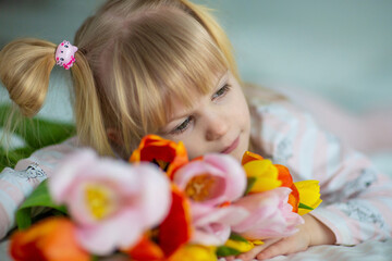Obraz na płótnie Canvas baby in pajamas with a bouquet of tulips
