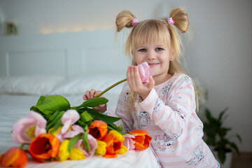 baby in pajamas with a bouquet of tulips