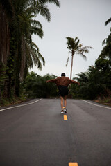 Girl in a brown leather jacket is on a paved road with a yellow stripe amongst the palm trees