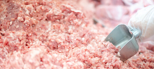 The supermarket employee preparing the Fresh pork meat slice on display tray for consumers select in a supermarket.