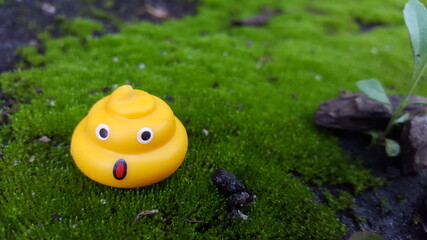Surprised Yellow Poop Emoji Toy on Moss