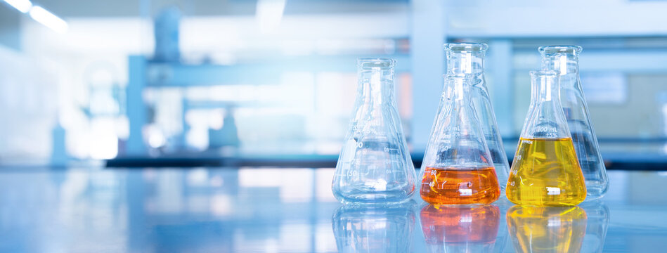 orange yellow solution in science glass flask win blue chemistry laboratory banner background