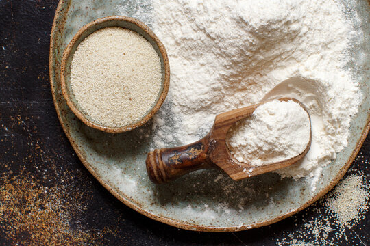 Raw fonio flour and seeds with a spoon on dark background