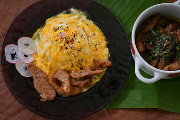 Omelet on top of rice with beef Basil on wood table brown colour with banana leaf