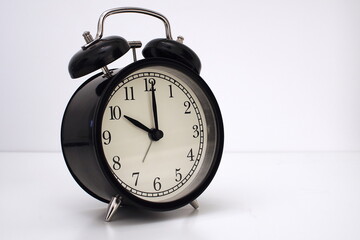 Black vintage alarm clock on table. White background. Wake up concept. An image of a retro clock...