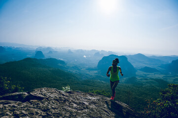 Fitness woman runner running  up to sunrise mountain peak