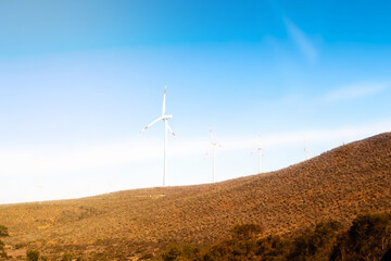 Wind turbine for green energy on hill with blue sky