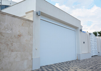 A close-up on a modern garage for cars with white garage door and lightning lamps.