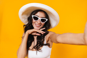 Fototapeta premium Image of cheerful woman smiling while taking selfie photo