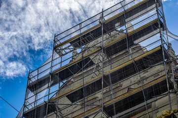 Facade of an old house in racks. Reconstruction of an old house with scaffolding.