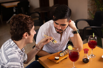 gay couple eating sushi in a restaurant