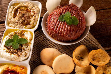 Raw quibe garnished with mint, Hummus, baba ganoush, onion and bread.