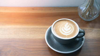 Latte Art Coffee Cup on a wooden table and warm light