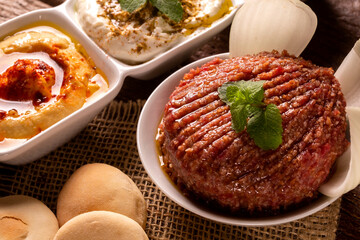 Raw quibe garnished with mint, Hummus, baba ganoush, onion and bread.