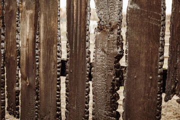 Burnt fence boards after a fire in a private house. The consequences of not careful and thoughtless handling of fire.