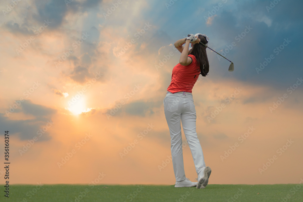 Wall mural Lady golfer playing golf during beautiful sunset.