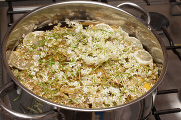 Elderflowers cooking in a pan of water with sugar and lemons to make a cordial