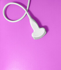 An ultrasound probe on pink background.