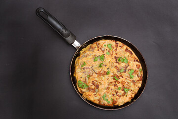 A Libyan potato omelette shot against a black studio background