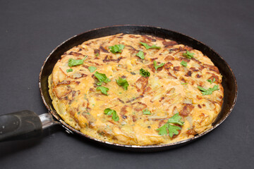 A Libyan potato omelette photographed on a black background