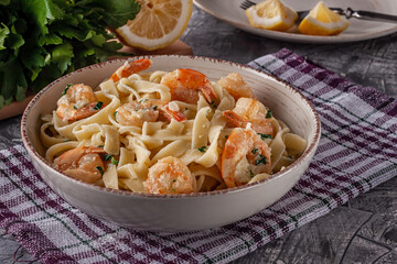 Tagliatelle with prawns and parsley on a gray background