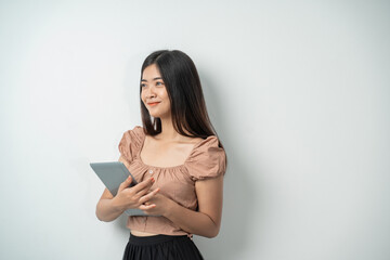 beautiful girl with long hair smiling while holding a tablet with an isolated background