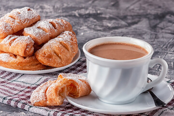 Coffee with cream and freshly baked puffs on a gray background