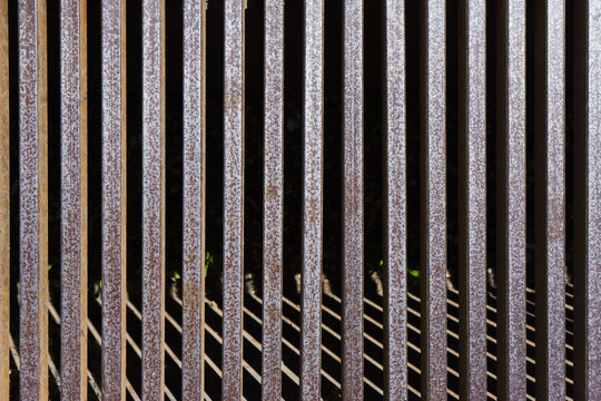 Iron grate over the drainage channel on the road. Rusty texture and scuffs on the metal. Metal grilles on the drainage system