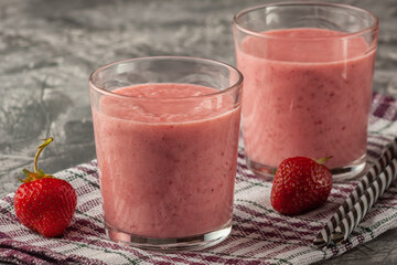Strawberry smoothie with milk in a glass on a gray background, healthy eating for breakfast and snacks