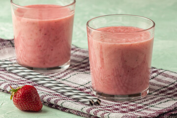 Strawberry smoothie with milk in a glass on a green background, healthy eating for breakfast and snacks