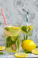 Refreshing drinks for summer, cold sweet and sour lemonade juice in the glasses with sliced fresh lemons. Refreshing summer drink. Traditional lemonade with lemon, mint and ice. Selective focus