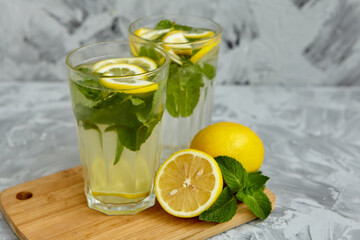 Refreshing drinks for summer, cold sweet and sour lemonade juice in the glasses with sliced fresh lemons. Refreshing summer drink. Traditional lemonade with lemon, mint and ice. Selective focus