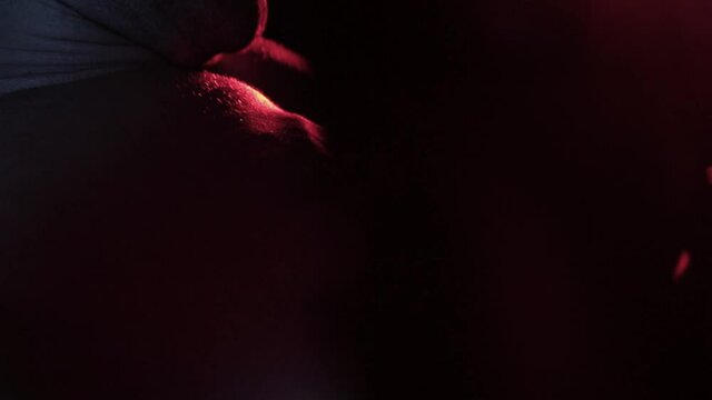 muscular man trains chest muscles in a dark gym on a simulator in red light