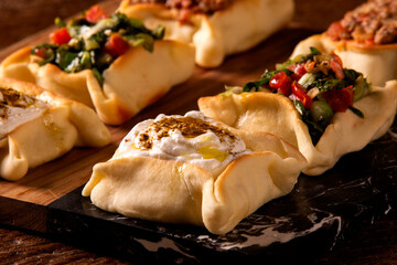 Varieties of Arabic sfihas open on rustic background. Meat, dry curd and endive.