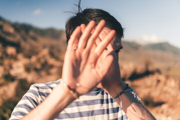 man covers his face with his hands. shy young man trying to hide from everyone.