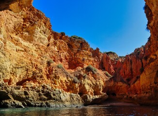 Fototapeta na wymiar Sandstone Cliff Cave near Carvoeiro with calm Atlantic Ocean. Beautiful Sea Cave in Algarve Coast, with Cave Hole Showing Blue Sky.