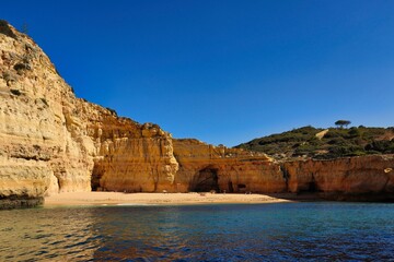 Fototapeta na wymiar Carvoeiro Beach with Sandstone Cliffs and Blue Sky in Algarve Coast. Classic Picture of a Beach near Benagil taken from a Boat.
