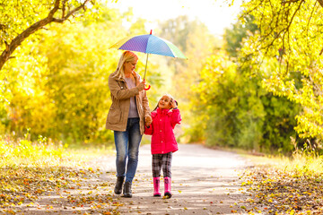 Young mother and her little daughter outdoors in colorful raincoats