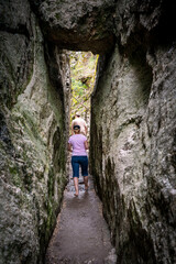 Fototapeta na wymiar A young man and a woman hike through a narrow stone passageway in the rocky Black Hills of South Dakota, USA.