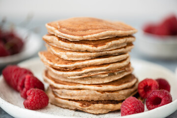 Stack of whole wheat pancakes with raspberries on plate, selective focus